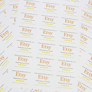 May include: A stack of white thank you cards with the text "Etsy" in orange and five yellow stars. The text "Thank you for shopping with us on Etsy. Please leave us a review." is printed on the cards.