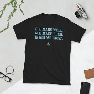 May include: Black t-shirt with a light blue graphic that says "God made weed. God made beer. In God we trust." and a colorful marijuana leaf.