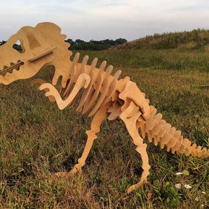 May include: A wooden dinosaur skeleton model, standing in a grassy field. The model is made of multiple pieces of wood that are assembled together to create the skeleton.