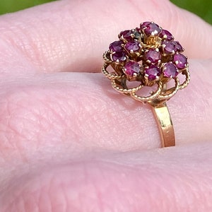 May include: A gold ring with a cluster of red gemstones set in a delicate, floral design.