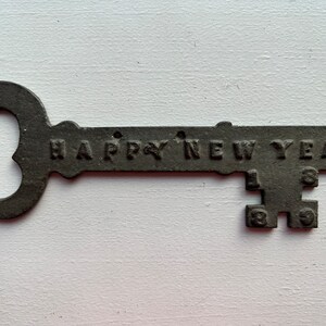 May include: A black metal key shaped ornament with the words "HAPPY NEW YEAR" and the year "1939" engraved on it.
