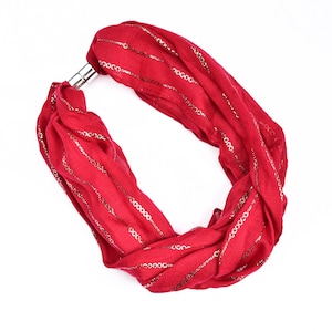 May include: A red scarf with gold metallic stripes and a silver clasp. The scarf is looped and appears to be made of a lightweight fabric. The gold stripes run horizontally across the scarf.