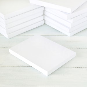 May include: A stack of white cardboard boxes on a white wooden surface. The boxes are all the same size and are arranged in a neat pile.