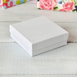 May include: A white square gift box with a textured surface.