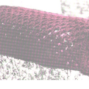 Könnte beinhalten: Nahaufnahme eines rechteckigen Kissens in dunkelrosa mit Textur. Das Kissen ist aus einem weichen, gewebten Stoff.