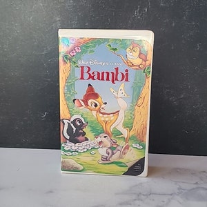 May include: A VHS tape featuring the Walt Disney Classic movie Bambi. The cover art features Bambi, Thumper, and Flower in a forest setting. The title "Bambi" is in red letters.