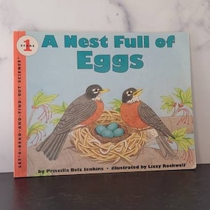 May include: A children's book titled "A Nest Full of Eggs" features illustrations of two robins near a nest with blue eggs. The book cover has a light blue background and the text "LET'S READ-AND-FIND-OUT SCIENCE".