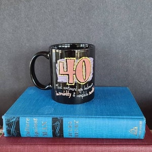 May include: Black coffee mug with a pink and yellow design that says "40 That awkward age between desirability & complete smelly"