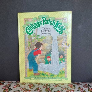 Puede incluir: Una portada de libro amarilla y verde con el título "Cabbage Patch Kids" y el subtítulo "Xavier's Fantastic Discovery". La portada presenta una ilustración de un niño mirando una cascada con un conejo y una abeja.