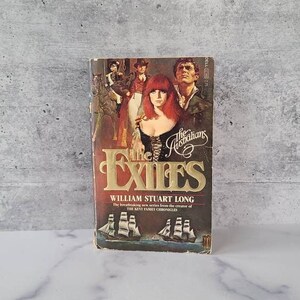 May include: A vintage paperback book titled "The Exiles" by William Stuart Long. The cover features a woman with red hair and illustrations of people and ships. The book is part of "The Australians" series.
