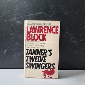 Puede incluir: Un libro de bolsillo titulado "Tanner's Twelve Swingers" de Lawrence Block. La portada presenta texto rojo y negro sobre un fondo crema, con una ilustración roja de una persona sentada. El libro es parte de la serie Evan Tanner.