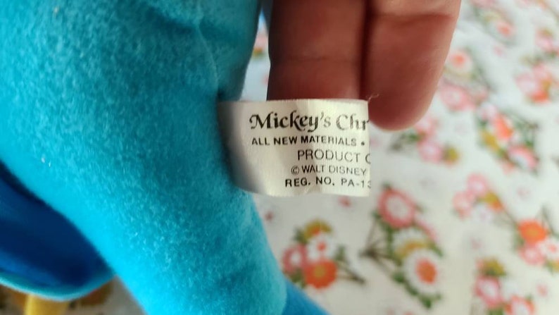 May include: A white tag with black text that reads "Mickey's Chr ALL NEW MATERIALS. PRODUCT C WALT DISNEY REG. NO. PA-13"