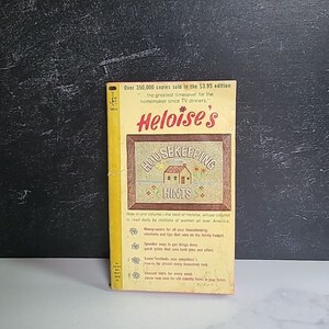 May include: A yellow and orange book cover with the title "Heloise's Housekeeping Hints". The book cover features a small illustration of a house with a red roof and a green lawn. The text on the cover reads "Over 350,000 copies sold in the $3.95 edition...the greatest timesaver for the homemaker since TV dinners."