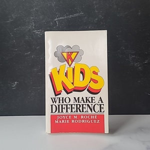 May include: A book titled "Kids Who Make a Difference" by Joyce M. Roche and Marie Rodriguez. The cover features a red and yellow illustration of a superhero with the letter "K" on their chest.