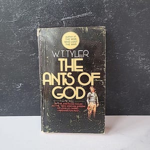 以下が含まれることがあります： W.T. タイラー著「神の蟻」の白黒の表紙。表紙には建物の前に立っている男性が描かれている。