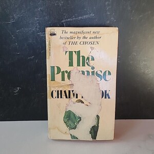 May include: A vintage paperback book titled "The Promise" by Chaim Potok. The cover is cream-colored with green and black text, and shows signs of wear. The book is a "Fawcett Crest Book."