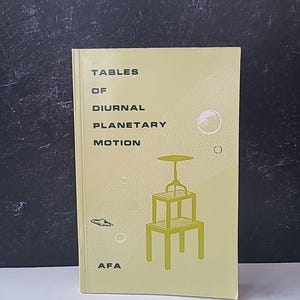 Puede incluir: Un libro antiguo titulado "Tables of Diurnal Planetary Motion" con una cubierta verde claro. La portada presenta una ilustración geométrica de una mesa y un cuerpo celeste. Las iniciales del autor, "AFA", están impresas en la parte inferior.