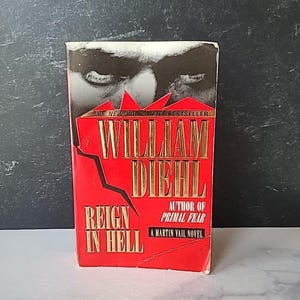 May include: A red paperback book with the title "Reign in Hell" by William Diehl, author of "Primal Fear". The book cover features a close-up of a man's eyes.