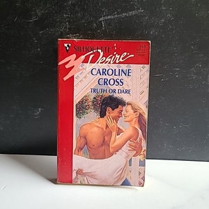 May include: A red paperback book with the title "Silhouette Desire" and the text "Caroline Cross Truth or Dare" on the cover. The cover features a couple embracing.