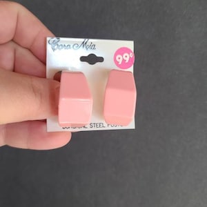 May include: A pair of pink plastic hoop earrings with a surgical steel post. The earrings are on a white card with the text "Bora Mia" and "99 cents".
