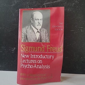 May include: A red book titled "Sigmund Freud New Introductory Lectures on Psycho-Analysis" with a portrait of Sigmund Freud. The book is a standard edition and includes a biographical introduction by Peter Gay.