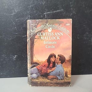 以下が含まれることがあります： Curtiss Ann Matlockの「Intimate Circle」というタイトルのヴィンテージペーパーバック。表紙には、野原で抱き合うカップルが描かれています。この本はSilhouette Special Editionシリーズの一部です。