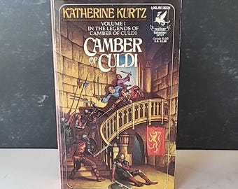 May include: A paperback book cover with a red spine and a yellow and brown illustration of a fight scene in a castle. The book title is "Camber of Culdi" and the author is Katherine Kurtz. The book is volume 1 in the Legends of Camber of Culdi series.