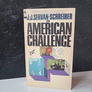 May include: A vintage paperback book titled "The American Challenge" by J.J. Servan-Schreiber. The cover features bold black text on a cream background, with illustrations of a cityscape and office setting. The book is marked as a 5-month national bestseller.