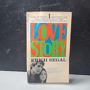 以下が含まれることがあります： エリック・シーガルの「ラブ・ストーリー」というタイトルのペーパーバック。表紙には、大きなカラフルな文字でタイトルと、男性と女性の写真が掲載されています。この本はニューヨーク・タイムズのベストセラーです。