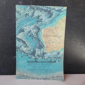 May include: A vintage National Geographic magazine cover featuring a detailed map of the Indian Ocean floor. The map shows the ocean floor's topography in shades of blue and tan, with the continent of Australia visible. The title "INDIAN OCEAN FLOOR" is prominently displayed.