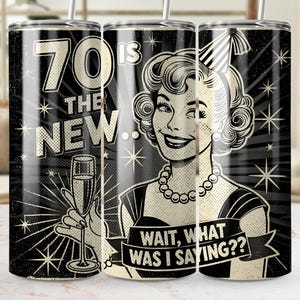 Op de afbeelding: Een zwart-witte beker met een retro-ontwerp. De beker heeft de tekst "70 is the new..." en een vintage illustratie van een vrouw die een champagneglas vasthoudt. De banner luidt "Wait, what was I saying??"