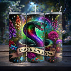 Op de afbeelding: Drie roestvrijstalen bekers met een levendig slangenontwerp. De slang is afgebeeld met groene, paarse en rode schubben, omringd door bloemen en de tekst "Lovely but Lethal" op een banner. De achtergrond heeft een sterrenhemel.