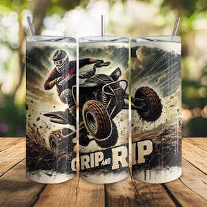 May include: A tumbler with a thrilling ATV scene, depicting a rider navigating muddy terrain. The design incorporates the words "Grip and Rip" in a striking font. The background shows a cloudy sky and a wooden surface.