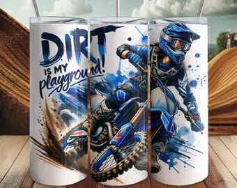 May include: White tumbler with a blue and white graphic of a motocross rider on a dirt bike. The tumbler has the text "DIRT is my playground" in blue. The design features splashes of blue and brown to depict dirt and motion.