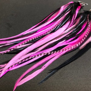 May include: A pair of long, black and pink feather earrings. The feathers are layered and have a delicate, wispy texture.