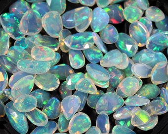Pode incluir: Uma coleção de opalas soltas, em forma de pêra, em vários tons de branco e azul e verde iridescente.