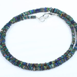 May include: A silver necklace with a silver clasp, featuring a double strand of dark green, blue, and iridescent black square-shaped opal beads.