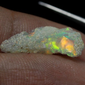 Può includere: Un opale verde chiaro grezzo con un bagliore di arancione e verde. L'opale è una pietra grezza non levigata.