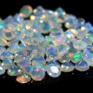 Pode incluir: Uma cole&ccedil;&atilde;o de pequenas opalas brancas transl&uacute;cidas e facetadas com flashes iridescentes de luz verde, azul e laranja. Cada pedra preciosa &eacute; cortada em formato triangular com m&uacute;ltiplas facetas que refletem a luz.