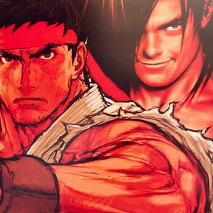 May include: A close-up of two men's faces. The man on the left has short black hair, a red headband, and a serious expression. The man on the right has long black hair, a smirk, and is wearing a torn white shirt.