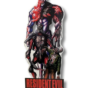 May include: A Resident Evil video game promotional cardboard cutout featuring three zombie-like figures. The tallest figure is red and blue with a menacing expression. The middle figure is a dark, skeletal creature with a large, gaping mouth. The bottom figure is a green-skinned zombie with a bloody mouth. The cutout has the words "Resident Evil" in red letters and the PlayStation logo and Capcom logo at the bottom.