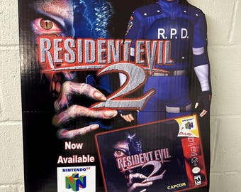 May include: A cardboard stand-up cutout advertisement for the video game Resident Evil 2 for the Nintendo 64. The cutout features a character from the game wearing a blue uniform with the letters R.P.D. on the chest. The character is holding a game cartridge for Resident Evil 2. The text "If the suspense doesn't kill you, something else will..." is at the top of the cutout. The text "Now Available" is at the bottom of the cutout.