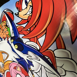 May include: A red and white cartoon character with a red mohawk and blue eyes. The character is in a fighting pose with a blue and white wing behind it. The character is surrounded by other cartoon characters.