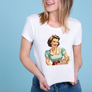 May include: White t-shirt with a vintage illustration of a woman in a blue and white polka dot dress holding a bowl of popcorn and a box of cereal. The text on the cereal box reads "Sugar Smacks".