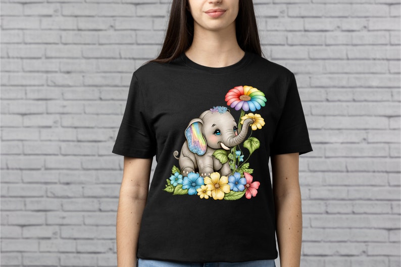 May include: A black t-shirt with a colorful illustration of a cartoon elephant with rainbow-colored ears and a rainbow flower. The elephant is surrounded by blue, yellow, pink, and green flowers.