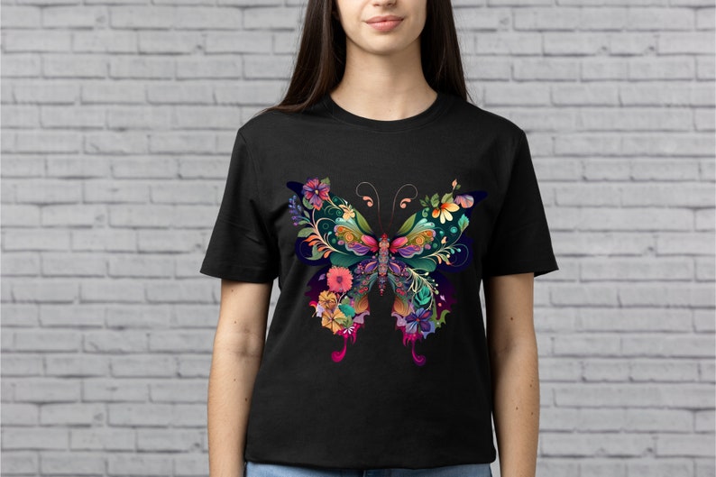 Op de afbeelding: Zwart T-shirt met een kleurrijk vlinderontwerp met bloemdetails. De vlinder is gemaakt van verschillende kleuren, waaronder roze, paars, blauw, groen en geel.