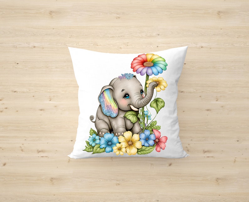 May include: A white pillow with a gray elephant with rainbow ears and a rainbow flower. The elephant is surrounded by colorful flowers and green leaves.