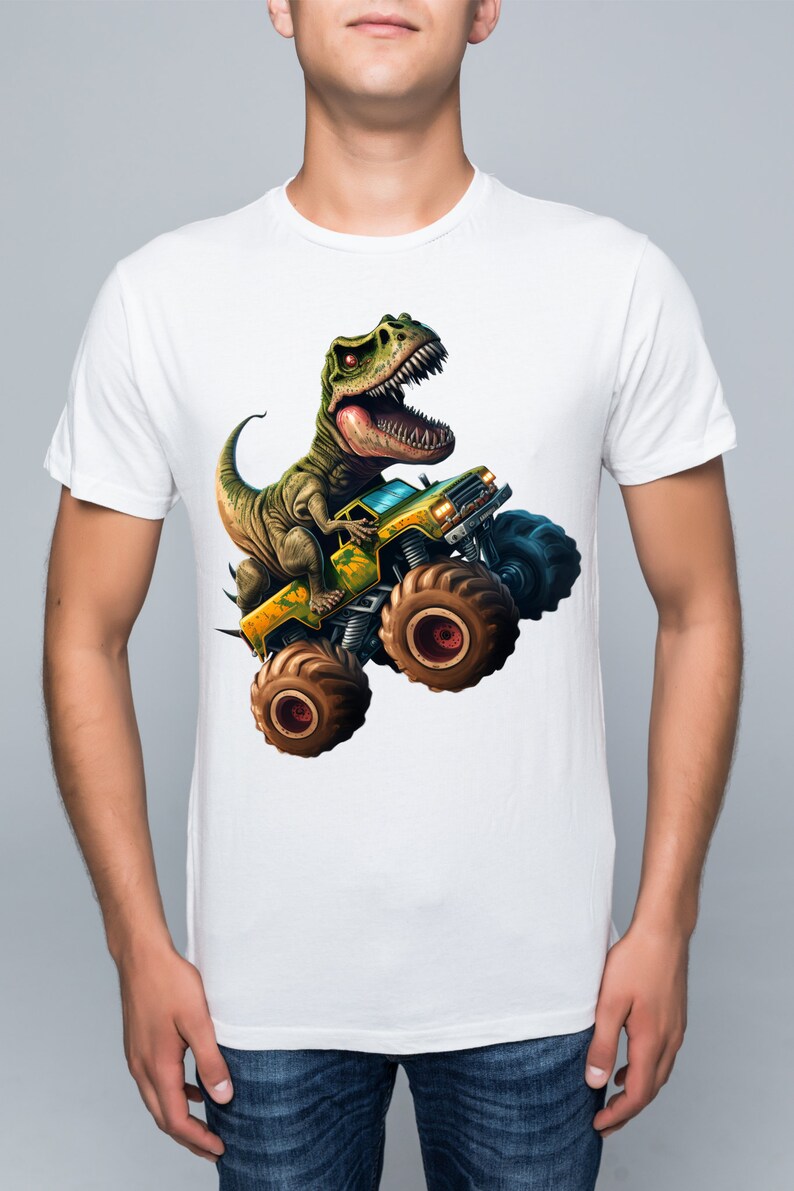 May include: White t-shirt with a green dinosaur riding a yellow monster truck with large tires.