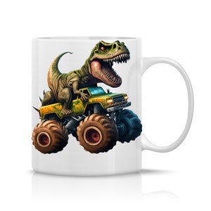 May include: A white ceramic mug with a green dinosaur riding a yellow monster truck. The dinosaur has a toothy grin and is holding onto the truck's cab.