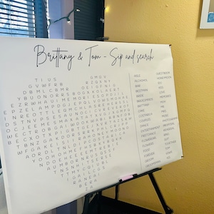 May include: A white board with the words "Brittany & Tom - Sip and Search" written at the top. The board has a word search puzzle with words related to a wedding, such as "bride", "groom", "love", and "honeymoon".